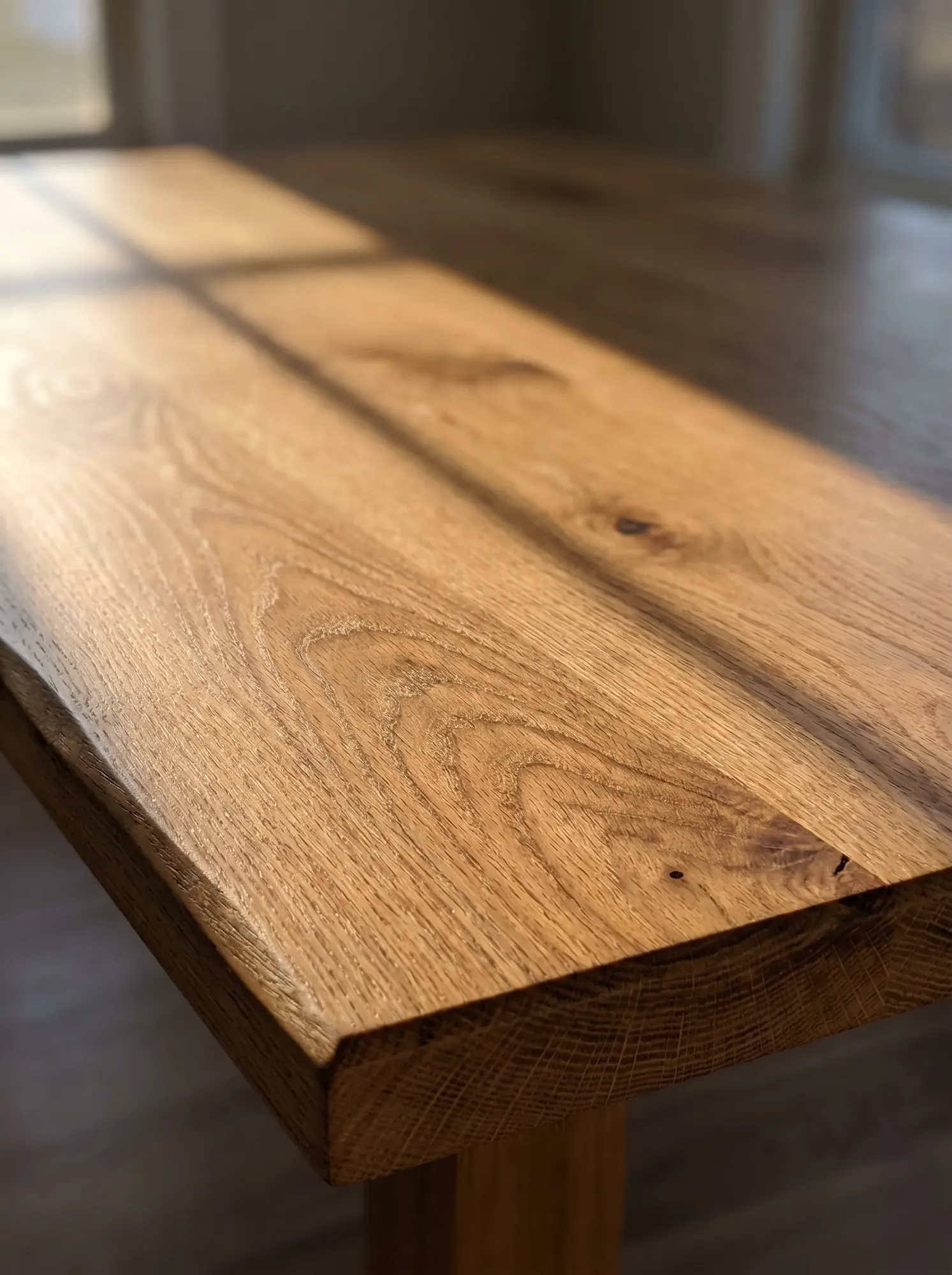 Sunlight moving across an oak tabletop with visible grain and hand-finished edge